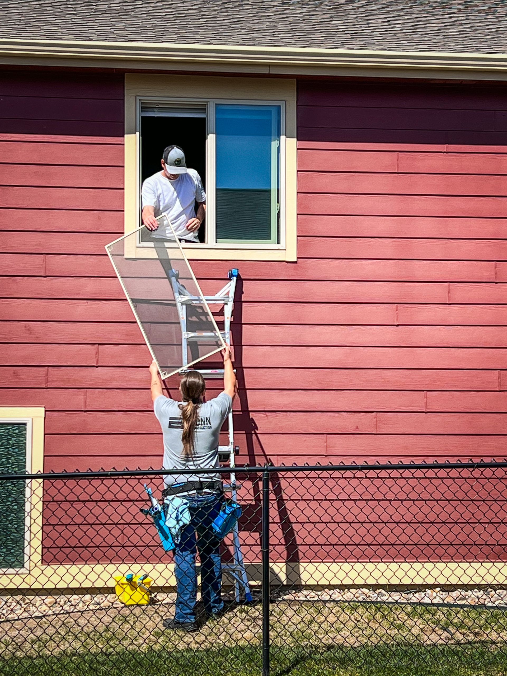 Gloved hands cleaning a window with a cloth and spray bottle